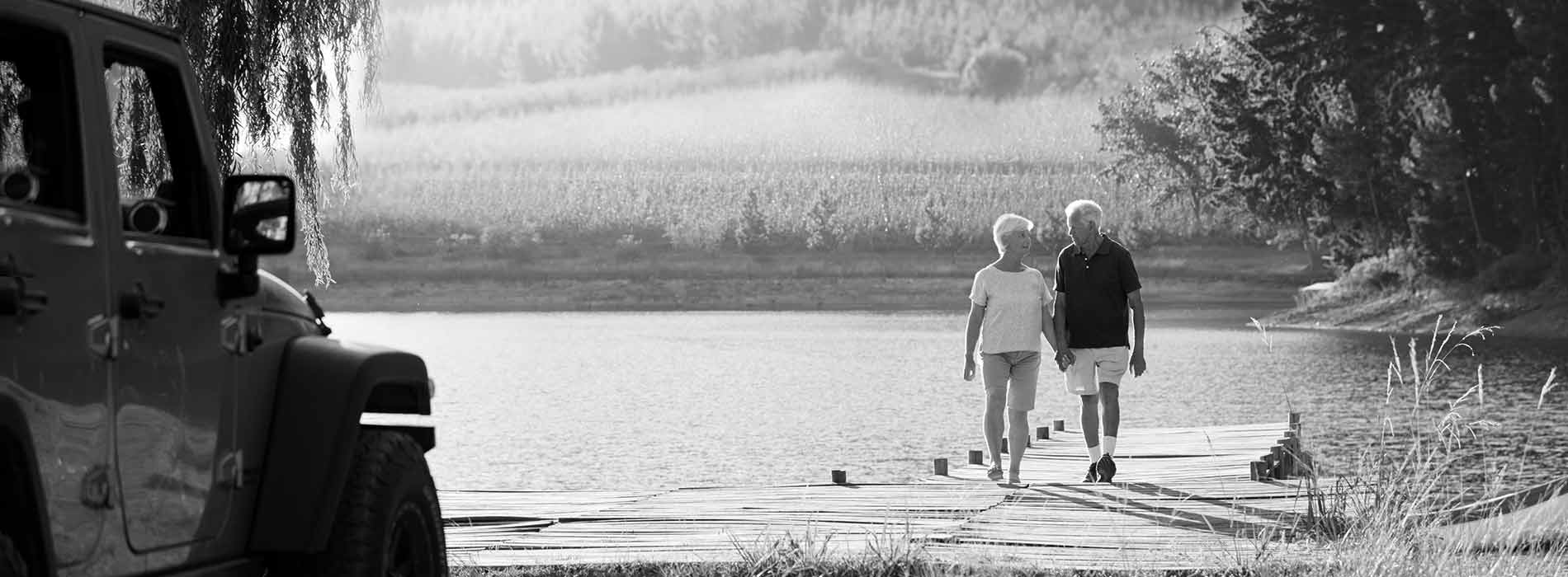 senior couple walking  on a lake dock towards their jeep